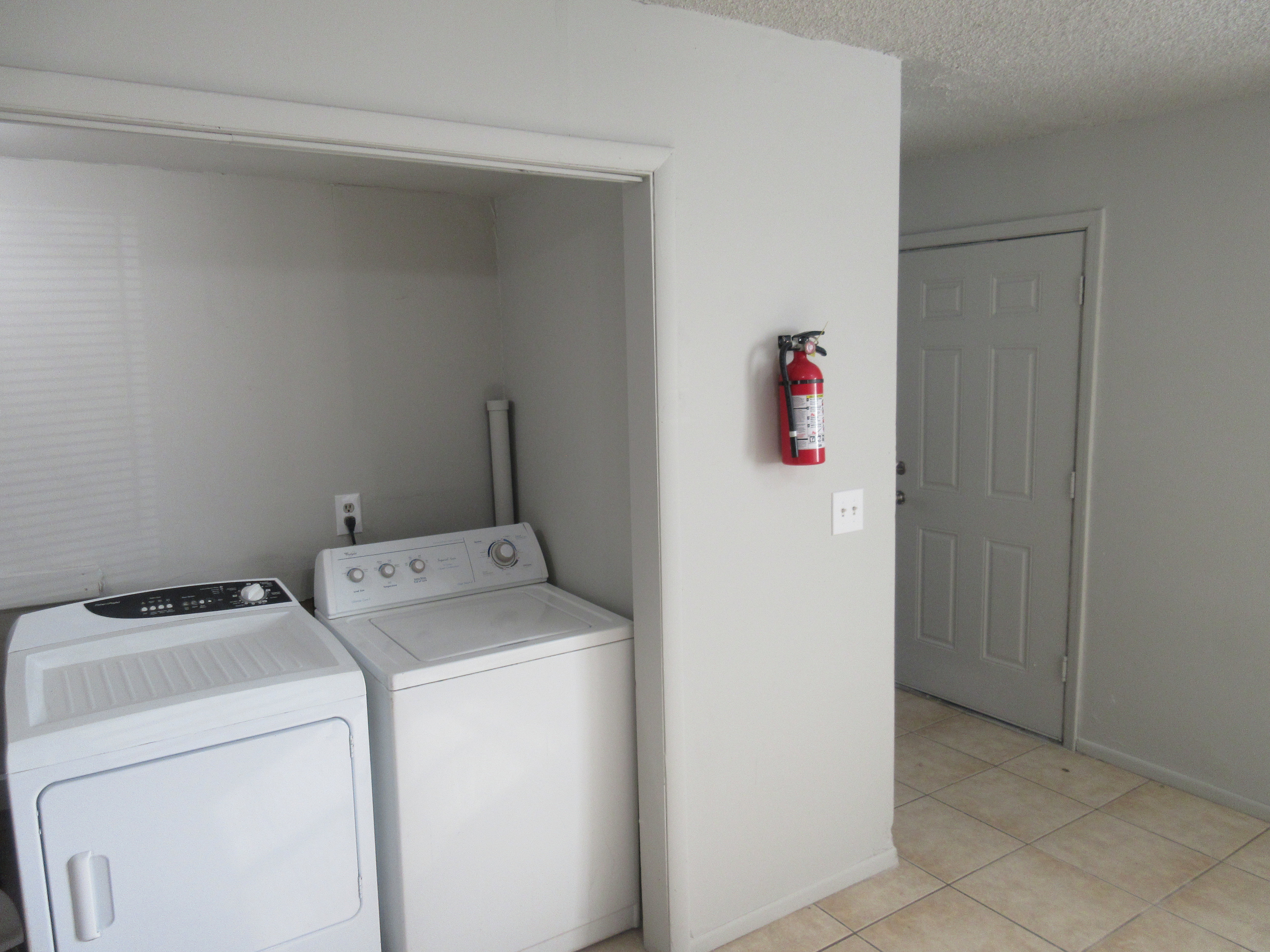 Laundry area with independent washer and dryer, a textured ceiling, and light tile patterned floors