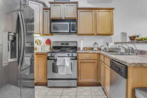 Kitchen with stainless steel appliances, light countertops, light tile patterned flooring, and a peninsula