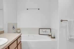 Full bath featuring a garden tub and vanity