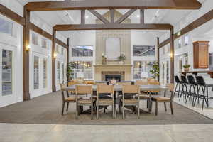Dining area with vaulted ceiling, a lit fireplace, plenty of natural light, and light carpet