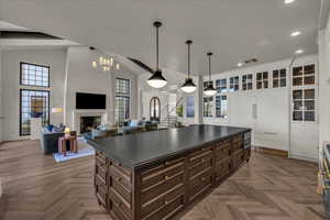 Dual tone kitchen with two tone cabinetry, parquet floors, open floor plan, a fireplace, and dark countertops