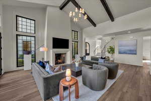 Living area with a fireplace, wood-type flooring, vaulted ceiling, and suspended lighting