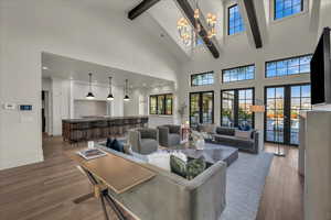 Living room with hardwood / wood-style flooring, suspended lighting, french doors, and vaulted ceiling