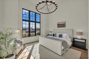 Bedroom with a high ceiling, wood finished floors, and hanging lights