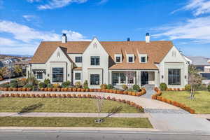 View of front of property featuring a chimney, a front lawn, stucco siding, and roof with shingles