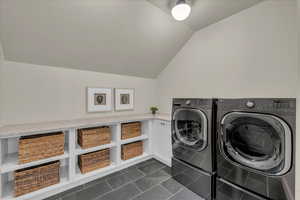 Laundry room featuring vaulted ceiling, independent washer and dryer, and dark tile patterned floors