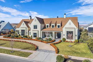 View of front facade featuring a chimney, a front lawn, a porch, and roof with shingles