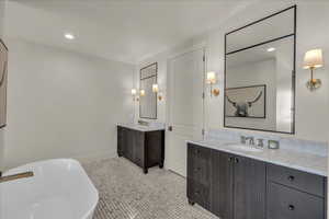 Bathroom featuring two vanities, a freestanding tub, and recessed lighting