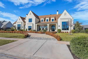View of front of property with a chimney, a front lawn, a porch, stucco siding, and roof with shingles