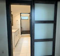 Full bath with light tile patterned flooring, a shower stall, and vanity