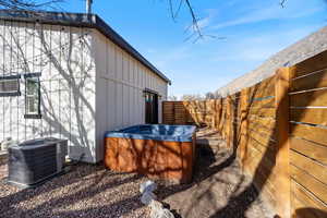 View of property exterior with a fenced backyard, a hot tub, and board and batten siding