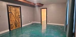 Unfurnished bedroom with concrete floors and a barn door