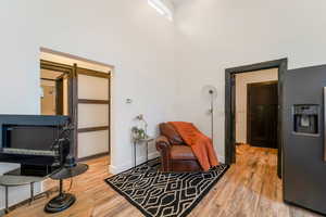 Sitting room featuring a high ceiling, light wood-type flooring, and a barn door