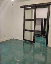 Empty room with a barn door and finished concrete flooring