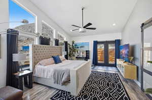 Bedroom featuring access to exterior, wood finished floors, a barn door, ceiling fan, and french doors