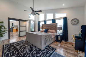 Bedroom featuring a barn door, wood finished floors, multiple windows, recessed lighting, and a ceiling fan