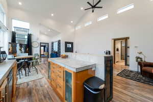 Kitchen featuring light wood-type flooring, open floor plan, light countertops, wood finish cabinets, and wine cooler