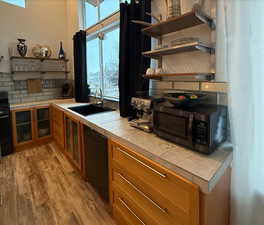 Kitchen featuring open shelves, black appliances, light countertops, and plenty of natural light