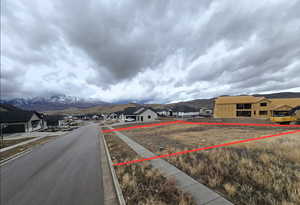 View of asphalt road with a residential view, a mountain view, sidewalks, and curbs