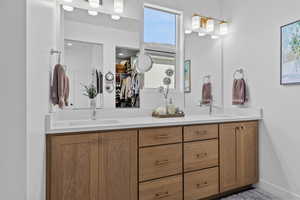 Bathroom with double vanity and a walk in closet