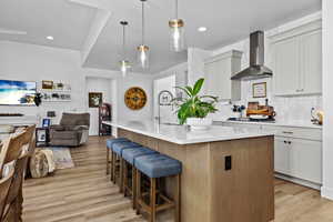 Two tone kitchen featuring hanging light fixtures, a kitchen bar, a center island with sink, backsplash, and dual tone cabinets