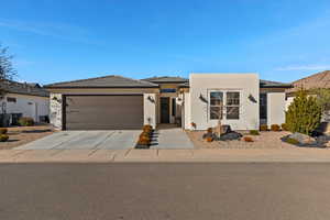 View of front of house with concrete driveway, stucco siding, a tile roof, and an attached garage