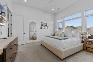 Bedroom with recessed lighting, arched walkways, light colored carpet, and a ceiling fan