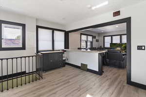 Kitchen with electric panel, light wood-style floors, light stone countertops, open floor plan, and a kitchen island