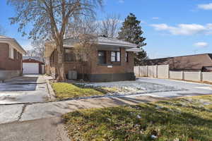 View of front of house with brick siding, a garage, an outbuilding, and a shingled roof