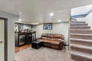Living area with a textured ceiling, a dry bar, recessed lighting, and wood finished floors