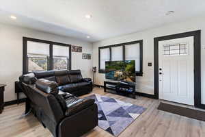 Living area with light wood finished floors, healthy amount of natural light, recessed lighting, and a textured ceiling