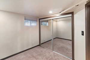 Unfurnished bedroom featuring a closet, light colored carpet, and elevator