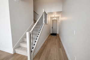 Stairs with wood finished floors and a chandelier
