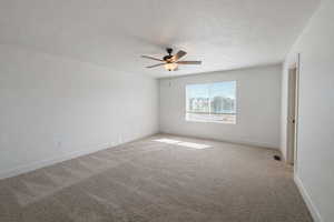 Carpeted spare room with ceiling fan and a textured ceiling