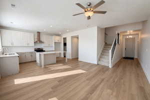 Kitchen featuring a kitchen island, open floor plan, gray cabinets, light wood finished floors, and a breakfast bar