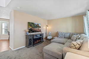 Carpeted living room with a textured ceiling and a warm lit fireplace