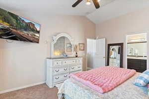 Bedroom with light colored carpet, lofted ceiling, ensuite bathroom, and a ceiling fan