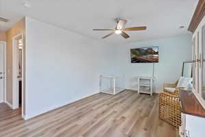 Sitting room featuring light wood-style flooring and a ceiling fan