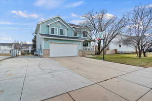Traditional-style home featuring a garage, concrete driveway, and brick siding