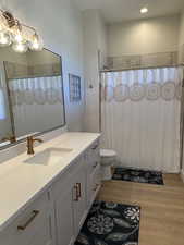 Bathroom with vanity, a shower with shower curtain, and light wood finished floors