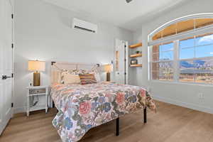 Bedroom with a mountain view, light wood-style flooring, and a ceiling fan