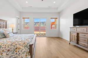 Bedroom featuring light wood-style floors, a tray ceiling, access to outside, ceiling fan, and recessed lighting