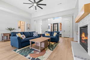 Living area with a stone fireplace, light wood-style floors, a ceiling fan, and recessed lighting