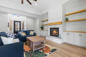 Living room with a fireplace, light wood-style floors, a ceiling fan, and recessed lighting