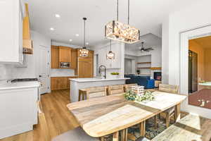 Dining room with ceiling fan, a chandelier, light wood finished floors, and a glass covered fireplace