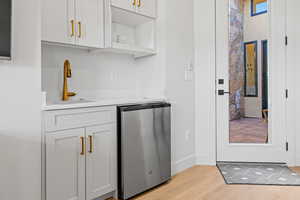 Bar area with open shelves, white cabinets, stainless steel fridge, and light wood-style flooring