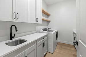 Laundry room with light wood-style flooring, cabinet space, and washer and clothes dryer