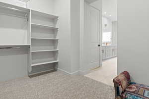 Walk in closet with light tile patterned floors and light carpet