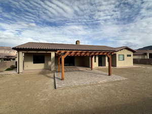 Rear view of house featuring a tiled roof, a patio area, stucco siding, and a pergola