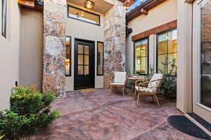 Entrance to property featuring stone siding, stucco siding, and a patio area